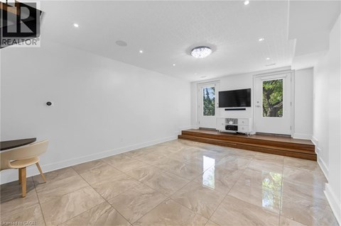 A spacious living room with a television and a window overlooking a tree.