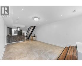 A spacious room with a wooden floor and a staircase.