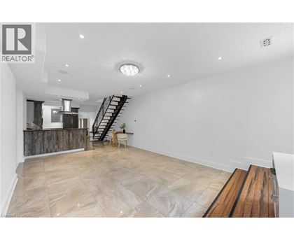 A spacious room with a wooden floor and a staircase.