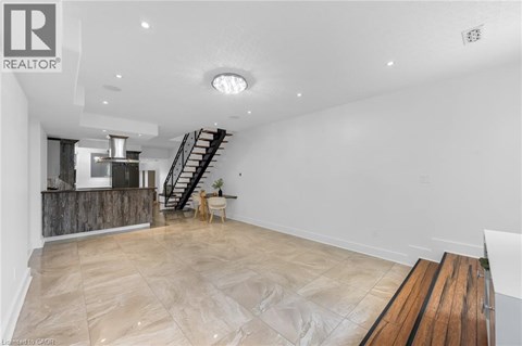 A spacious room with a wooden floor and a staircase.