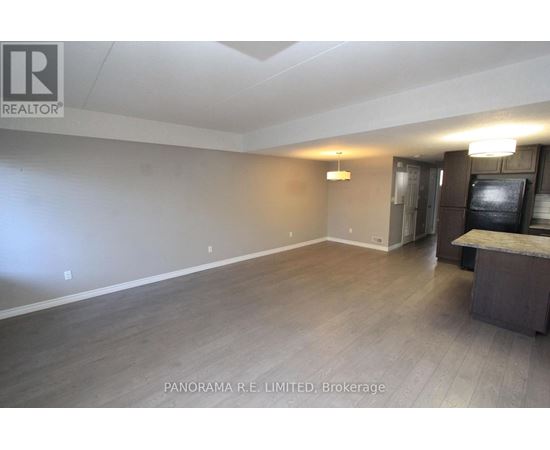 A spacious room with wood flooring and a bar area.