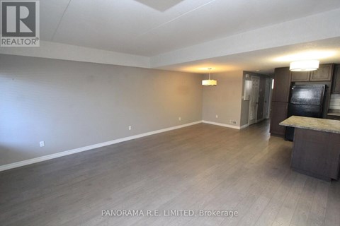 A spacious room with wood flooring and a bar area.