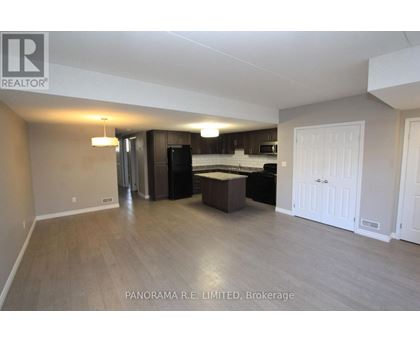 A spacious living room with a kitchen in the background.