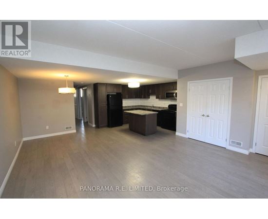 A spacious living room with a kitchen in the background.
