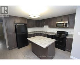 A kitchen with a black fridge, black oven, and black microwave.