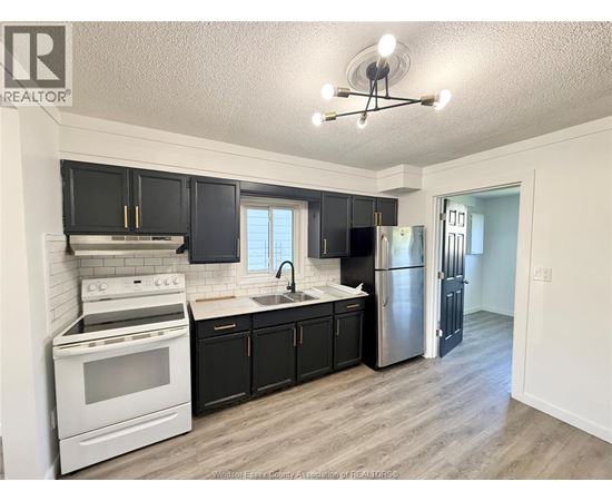 A kitchen with black cabinets and a white stove top oven.