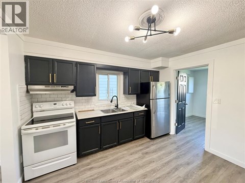 A kitchen with black cabinets and a white stove top oven.