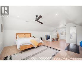 A bedroom with a bed, a ceiling fan, and a rug on the floor.