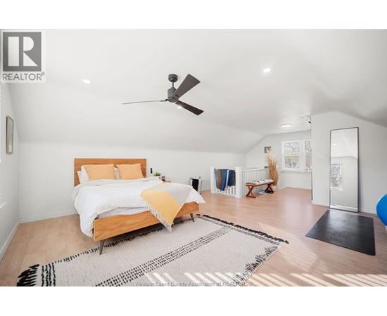 A bedroom with a bed, a ceiling fan, and a rug on the floor.