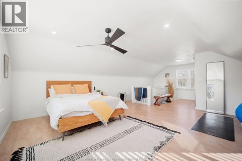 A bedroom with a bed, a ceiling fan, and a rug on the floor.