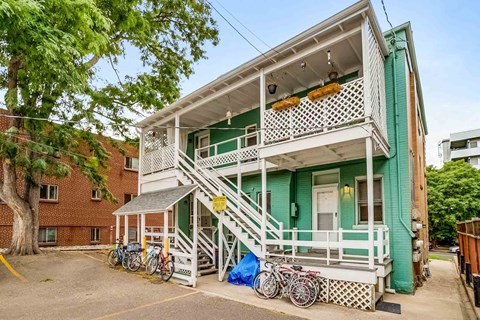 A green and white two-story house with a bicycle parked in front.