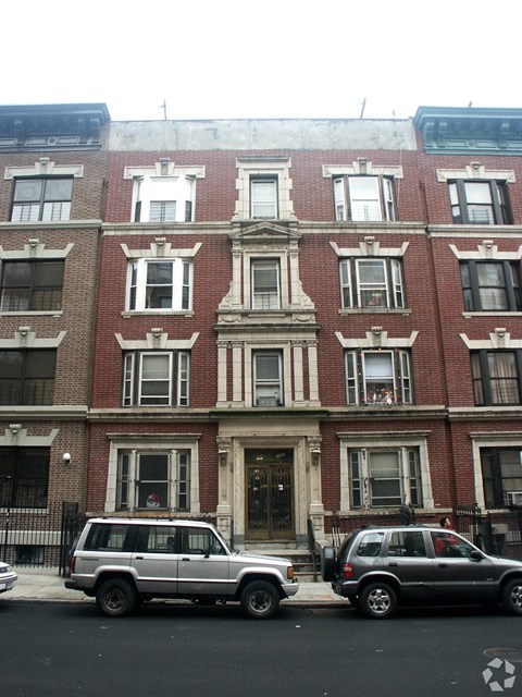Two cars are parked in front of a red brick building.