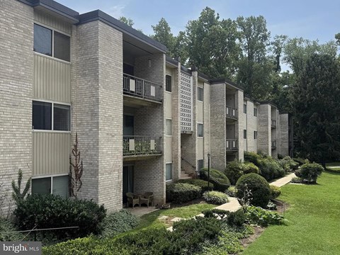 A row of apartment buildings with balconies and greenery in front.