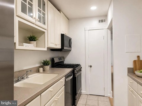 A kitchen with white cabinets and a black stove top oven.