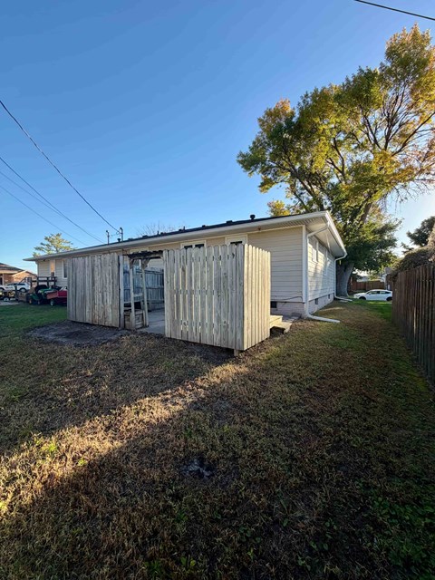 A shed with a damaged roof sits in a grassy area.