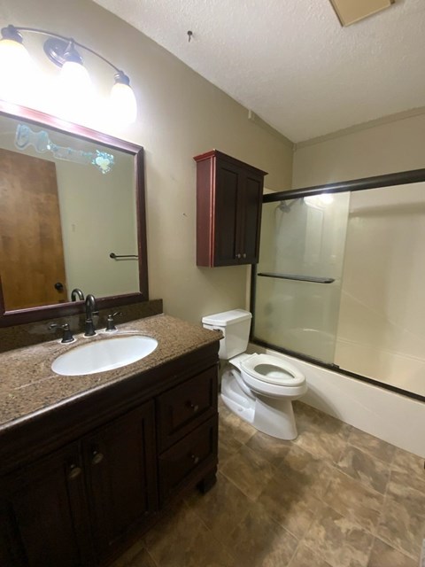 A bathroom with a toilet, sink, and mirror.
