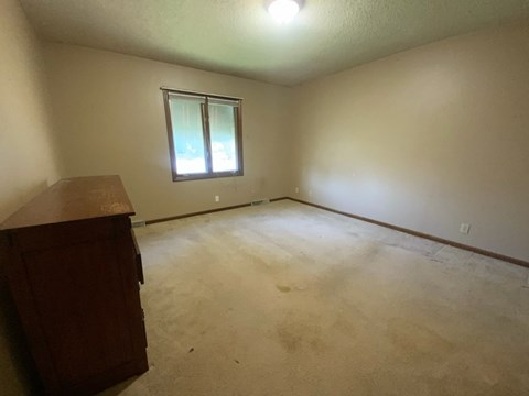 A room with a window and a brown cabinet.