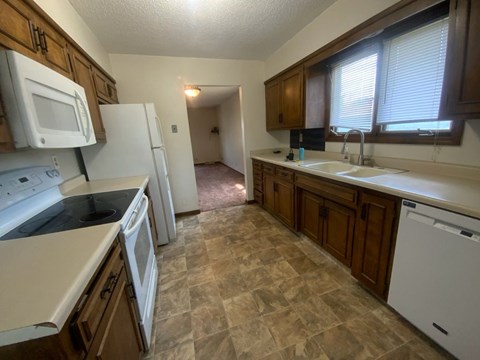 A kitchen with white appliances and brown cabinets.