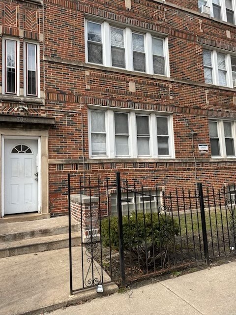 A red brick building with a white door and a black fence.