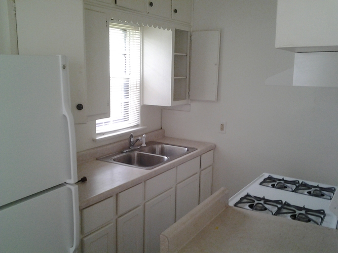 A white kitchen with a sink and a gas stove.