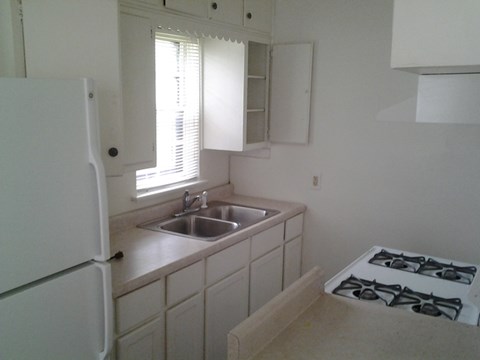 A white kitchen with a sink and a gas stove.