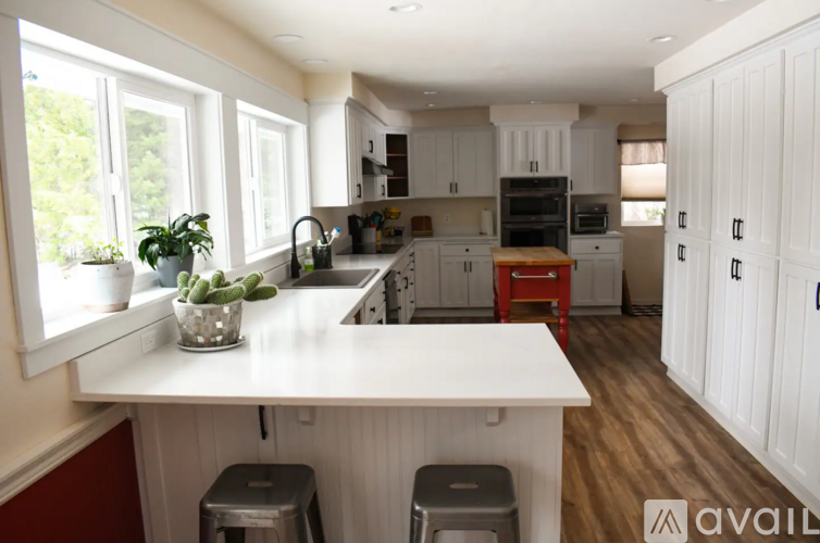A kitchen with white cabinets and a white island with a plant on it.