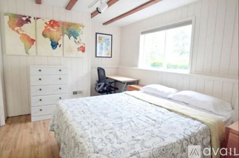 A bedroom with a world map on the wall and a bed with a white comforter.