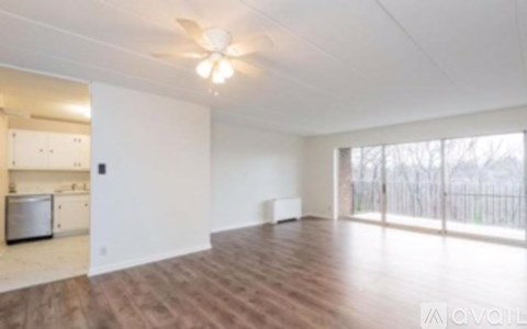 A spacious room with wooden floors and a ceiling fan.