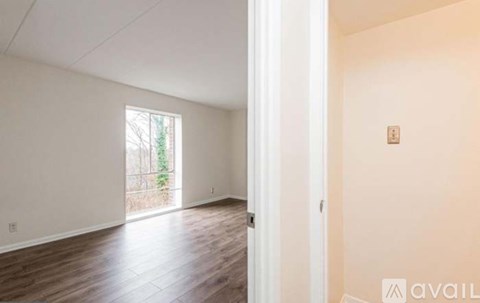 A room with wooden floors and a window showing trees outside.