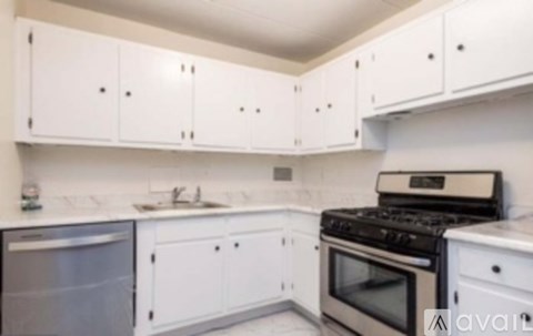 A kitchen with white cabinets and a black stove top oven.