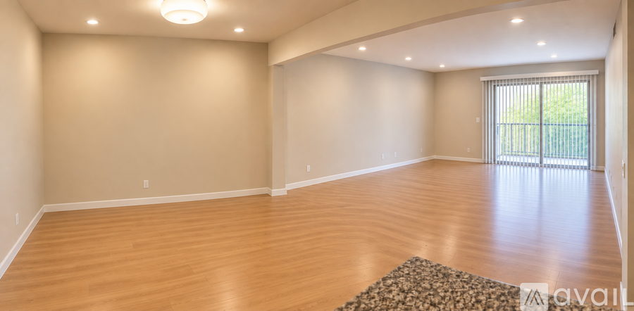 A large empty room with wooden floors and a sliding glass door.