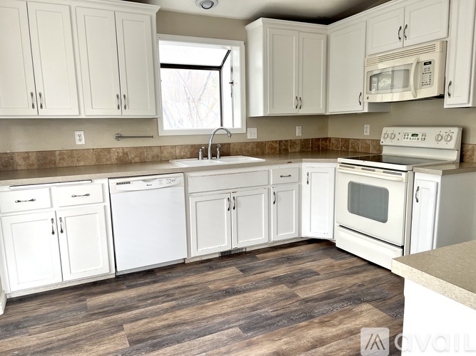 A kitchen with white appliances and cabinets.