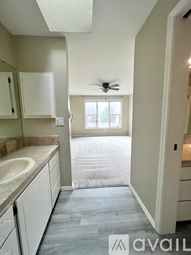 A bathroom with a sink, mirror, and a fan.
