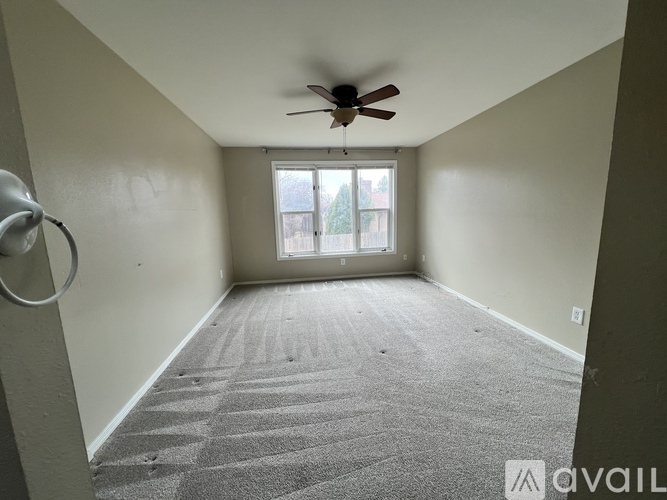 A room with a ceiling fan and carpeted floor.