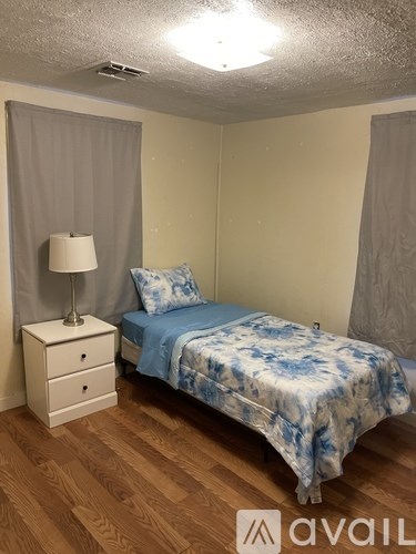 A bedroom with a bed, nightstand, and lamp.