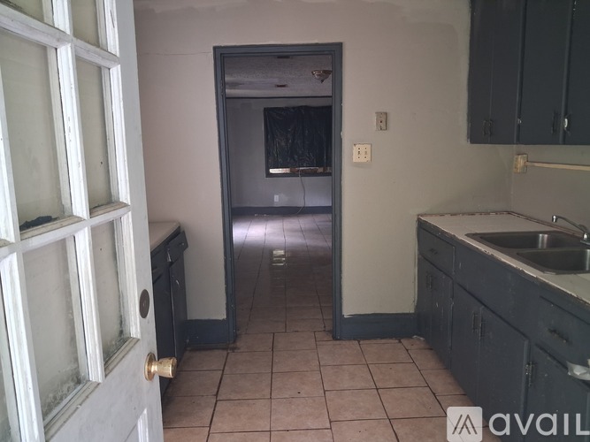 A kitchen with a sink and a door leading to a hallway.