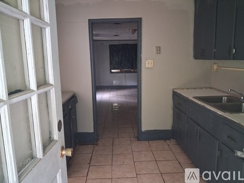 A kitchen with a sink and a door leading to a hallway.