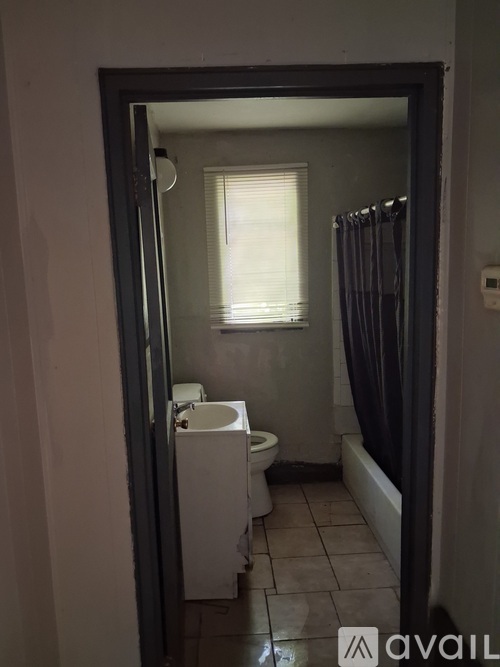 A bathroom with a toilet, sink, and window.