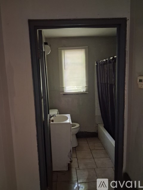 A bathroom with a toilet, sink, and window.