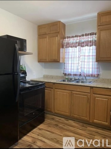A kitchen with wooden cabinets and a black refrigerator.
