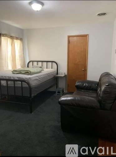 A bedroom with a bed, a couch, and a door.
