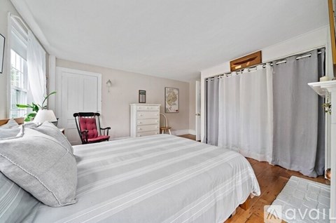 A bedroom with a bed, chair, and window.