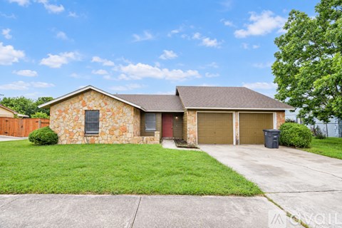 A house with a stone exterior and a brown roof with a garage door.