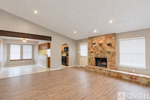 A spacious living room with a stone fireplace and hardwood floors.