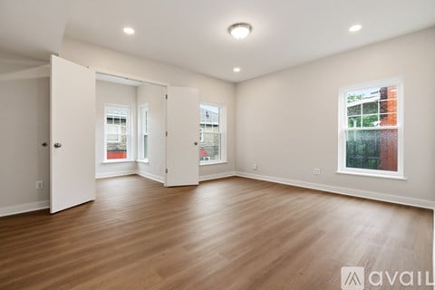 A spacious room with wooden floors and a large window.