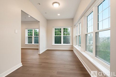 A spacious room with wooden floors and large windows.