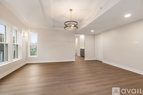 A spacious room with wooden floors and a hanging light fixture.