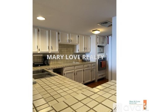 A kitchen with a tile counter top and white cabinets.