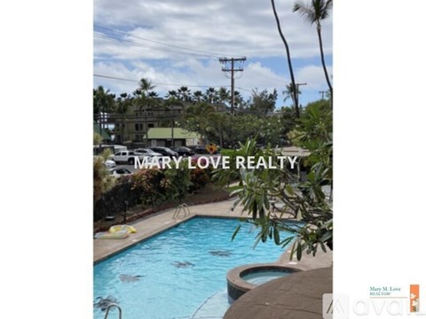 A swimming pool surrounded by trees and a house in the background.