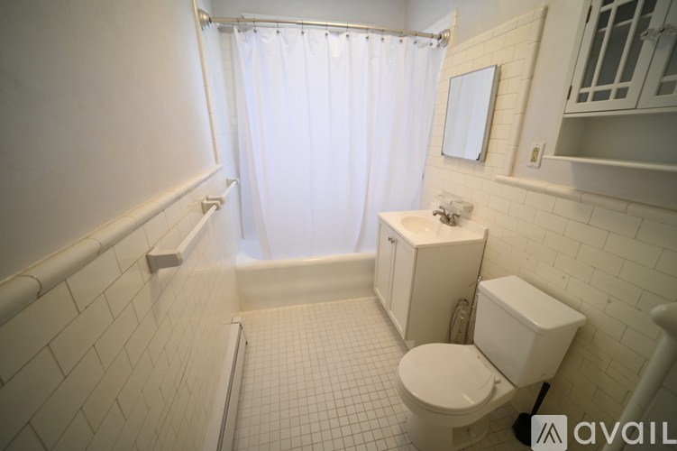 A white bathroom with a toilet, sink, and shower.